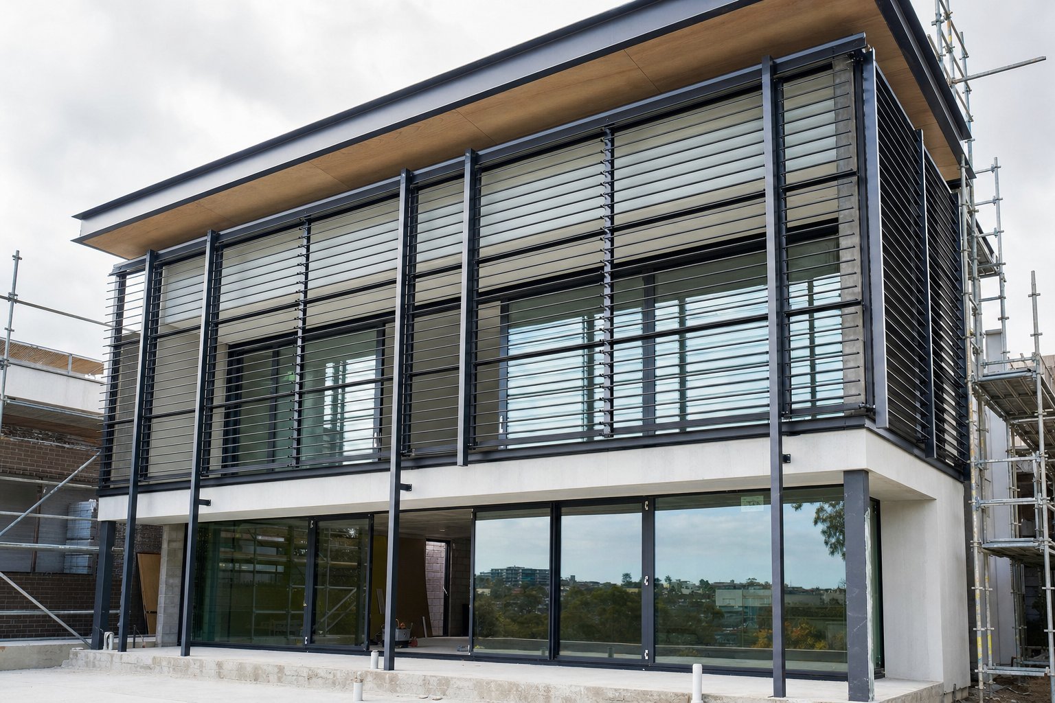 aluminium louvre installation showing stand off bracket mounting ahead of floor to ceiling glazing