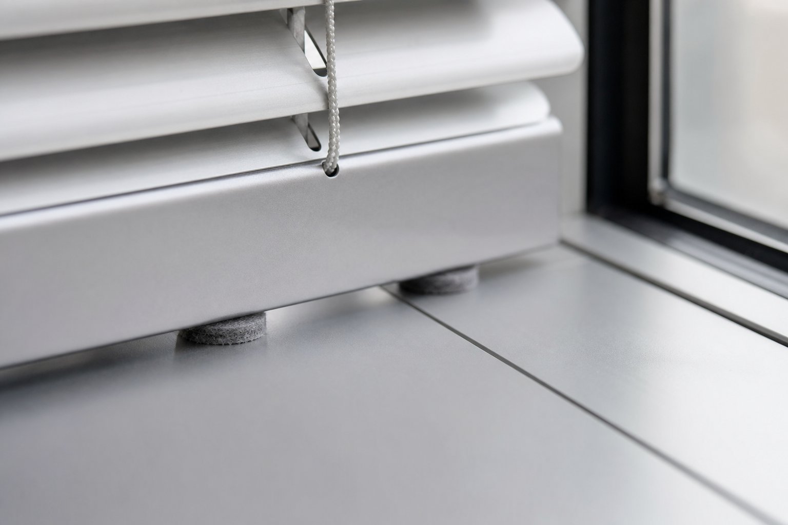 felt buffer pads placed between a venetian blind bottom rail and aluminium frame to prevent rattling