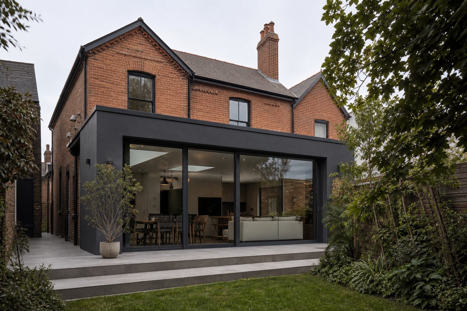 anthracite grey aluminium frames on a period home extension creating deliberate contrast between heritage and contemporary design